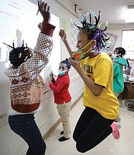 Niambi Cameron, 9, celebrates with classmates in March after answering a question during a math lesson at the Kilombo Academic and Cultural Institute in Decatur, Ga.,