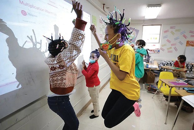 Niambi Cameron, 9, celebrates with classmates in March after answering a question during a math lesson at the Kilombo Academic and Cultural Institute in Decatur, Ga.,