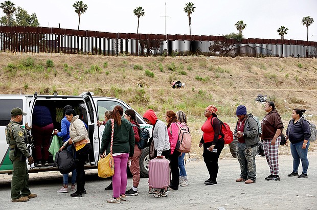 A Border Patrol agent keeps watch as immigrants enter a vehicle to be transported from a makeshift camp on May 13, 2023 in San Diego, California.
Mandatory Credit:	Mario Tama/Getty Images
