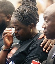 The mother of Irvo Otieno, Caroline Ouko, center, wipes a tear as his brother, Leon Ochieng, left, consoles his mother while Wednesday they are seated with Attorney Benjamin Crump during the Justice for Irvo Otieno Town Hall at Virginia Union University’s Claude G. Perkins Living & Learning Center.
