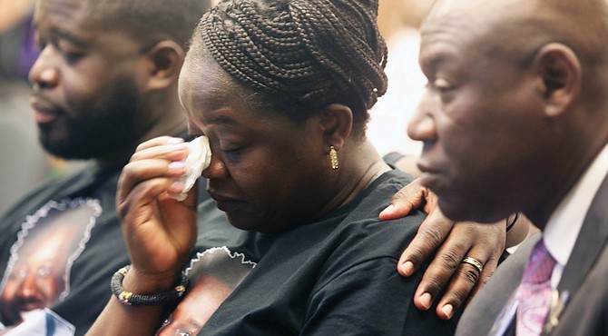 The mother of Irvo Otieno, Caroline Ouko, center, wipes a tear as his brother, Leon Ochieng, left, consoles his mother while Wednesday they are seated with Attorney Benjamin Crump during the Justice for Irvo Otieno Town Hall at Virginia Union University’s Claude G. Perkins Living & Learning Center.