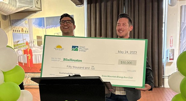 Joe Cutrufo, BikeHouston Executive Director, and Johnny Richardson, Green Mountain Energy Program Manager, smile with a $50,000 Green Mountain Energy Sun Club check for BikeHouston at the Houston Bike Summit Soirée on May 24.