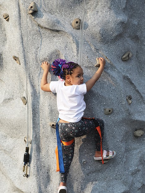 Calliope Snead, 5, of Church Hill, shows no fear as she looks over her shoulder for her mom, Tiffany Snead, cheering her on as she masterfully places her feet on the wedges as she climbs The Wall, a new attraction this year at the Robinson Theater’s Annual Block Party Friday, June 9, at 2903 Q St. in Richmond’s Church Hill.