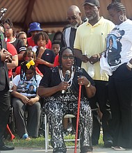 Grenda Smith, center, speaks at a June 11 vigil in Abner Clay Park for her son, Renzo Dell Smith, who was killed in front of the Altria Theater with his stepson, Shawn Jackson, following Huguenot High School’s graduation. Charles Willis, left, founder of United Communities Against Crime, shows his support for the grieving family.