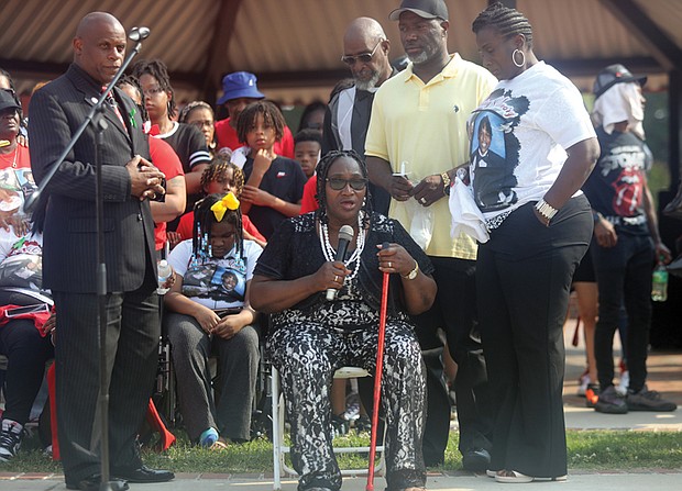 Grenda Smith, center, speaks at a June 11 vigil in Abner Clay Park for her son, Renzo Dell Smith, who was killed in front of the Altria Theater with his stepson, Shawn Jackson, following Huguenot High School’s graduation. Charles Willis, left, founder of United Communities Against Crime, shows his support for the grieving family.