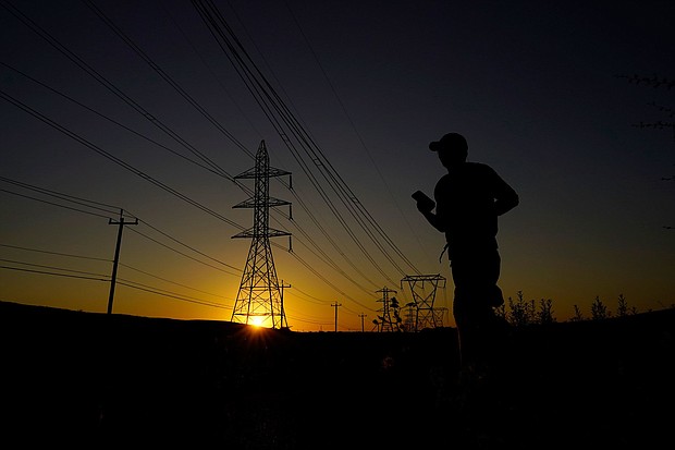A jogger passes under power lines during an evening run on Monday in San Antonio. Nighttime temperatures will stay dangerously hot this week, forecasters have warned.
Mandatory Credit:	Eric Gay/AP