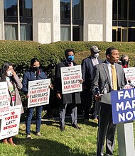 Voting rights activist Reggie Weaver, at podium, speaks outside the Legislative Building in Raleigh, N.C., Feb. 15, 2022, about a partisan gerrymandering ruling by the North Carolina Supreme Court. The Supreme Court has ruled that North Carolina’s top court did not overstep its bounds in striking down a congressional districting plan as excessively partisan under state law.