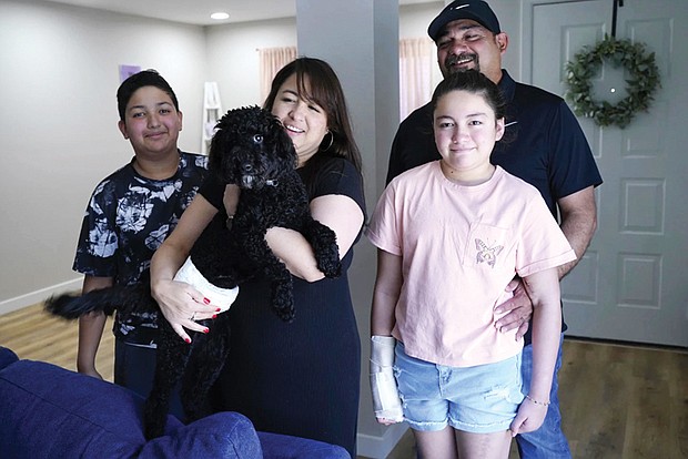 Mayah Zamora, front right, a survivor of the mass shooting at Robb Elementary in Uvalde, Texas, poses for a photo with her brother Zach, left, mom Christina, dad Ruben, back right, and her service dog Rocky at their home in San Antonio.