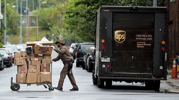 A delivery man pushes a cart full of packages to deliver to an apartment building.
Mandatory Credit:	Andrew Harnik/AP/FILE