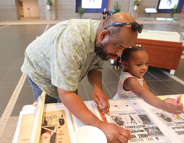 Naomi Folks, 3, and her father, Royce Folks, both of Midlothian, enjoy an art activity during the Virginia Folklife Program of Virginia Humanities celebration last Saturday at the Library of Virginia. In between the fun activities, Naomi delighted the crowd with her moves while dancing to the sounds of Kadencia’s Afro-Puerto Rican music.