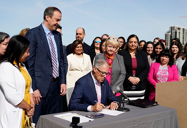 Washington Gov. Jay Inslee prepares to sign House Bill 1340, which protects health care providers in Washington from disciplinary action for providing legal abortion and gender-affirming care in Washington, April 27, at the University of Washington's Hans Rosling Center for Population Health in Seattle.
Mandatory Credit:	Lindsey Wasson/AP