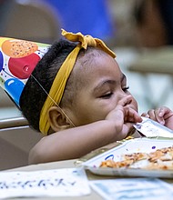 One-year-old Alivia Campbell enjoys pizza and a Capri Sun last Saturday during the Maggie L. Walker 159th birthday celebration at Third Street Bethel AME Church in Jackson Ward. The event was a part of a three-day celebration that featured a short film on the life of Maggie Walker, a wreath ceremony and walking tour of the Maggie Walker House.
