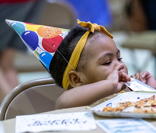 One-year-old Alivia Campbell enjoys pizza and a Capri Sun last Saturday during the Maggie L. Walker 159th birthday celebration at Third Street Bethel AME Church in Jackson Ward. The event was a part of a three-day celebration that featured a short film on the life of Maggie Walker, a wreath ceremony and walking tour of the Maggie Walker House.