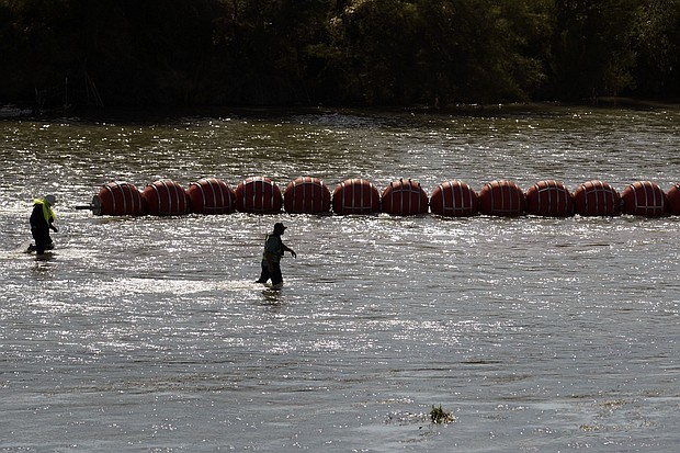 Workers help deploy a string of large buoys to be used as a border barrier at the center of the Rio Grande near Eagle Pass, Texas, July 11. The floating barrier is being deployed in an effort to block migrants from entering Texas from Mexico.
Mandatory Credit:	Eric Gay/AP