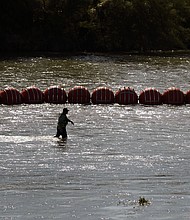 Workers help deploy a string of large buoys to be used as a border barrier at the center of the Rio Grande near Eagle Pass, Texas, July 11. The floating barrier is being deployed in an effort to block migrants from entering Texas from Mexico.
Mandatory Credit:	Eric Gay/AP
