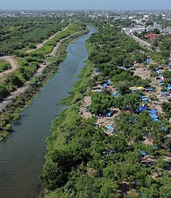 A makeshift camp, where asylum seekers wait as they attempt to cross into the US, lines the Rio Grande river border between Brownsville, Texas and Matamoros, in Matamoros, Mexico, on June 20.
Mandatory Credit:	Daniel Becerril/Reuters