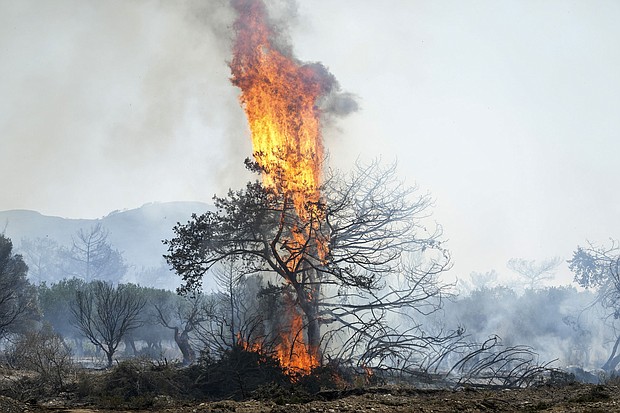 Flames burn a tree in Vati village, on the Aegean Sea island of Rhodes, southeastern Greece, on Tuesday, July 25.
Mandatory Credit:	Petros Giannakouris/AP