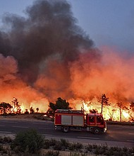 A fire truck moves along a road as a forest fire rages near the town of Melloula in northwestern Tunisia on July 24.
Mandatory Credit:	Fethi Belaid/AFP/Getty Images