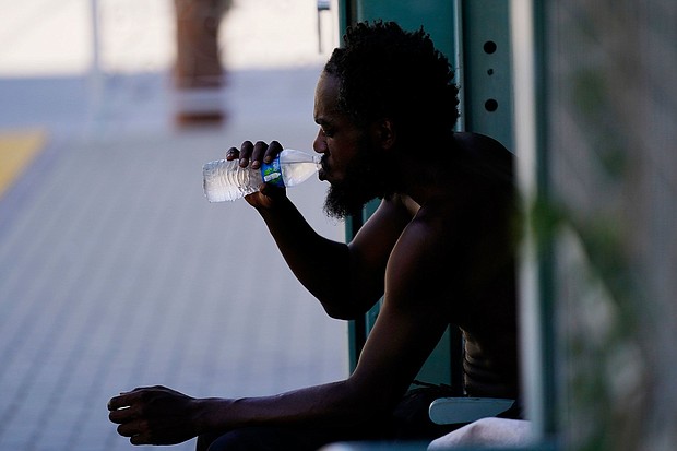 A person drinks a bottle of water in the shade as temperatures are expected to hit 119-degrees Thursday, July 20, in Phoenix.
Mandatory Credit:	Ross D. Franklin/AP