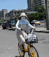 A woman wearing sun protective clothing rides a bike during hot weather conditions in Beijing on July 6.
Mandatory Credit:	Jade Gao/AFP/Getty Images