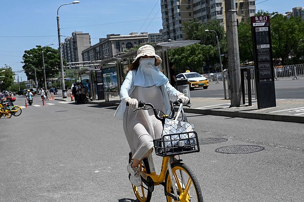 A woman wearing sun protective clothing rides a bike during hot weather conditions in Beijing on July 6.
Mandatory Credit:	Jade Gao/AFP/Getty Images