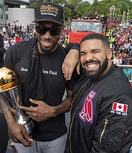 Toronto Raptors Kawhi Leonard, left, holds his MVP trophy while smiling for the camera with rapper/producer Drake as they celebrate during the team’s 2019 NBA basketball championship during a parade in Toronto.