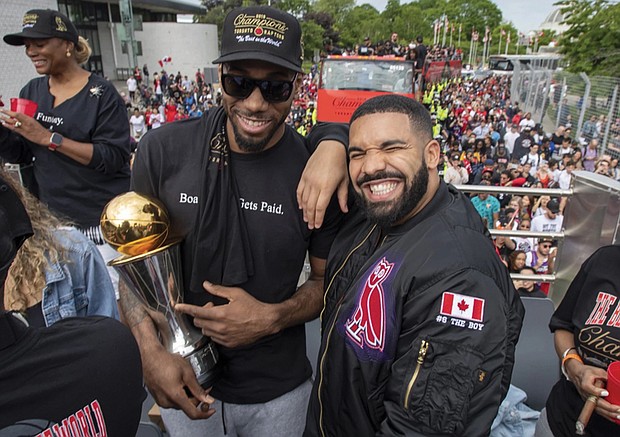 Toronto Raptors Kawhi Leonard, left, holds his MVP trophy while smiling for the camera with rapper/producer Drake as they celebrate during the team’s 2019 NBA basketball championship during a parade in Toronto.