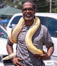 Tyrone Sherman, a professional reptile handler with Pixotics, poses above with one of his Albino pythons.