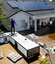 Nick Rodriguez stands on top of an outdoor barbecue seating area at his brother's flooded backyard from the remnants of tropical storm Hilary on August 21 in Cathedral City, California.
Mandatory Credit:	Gina Ferazzi/Los Angeles Times/Getty Images