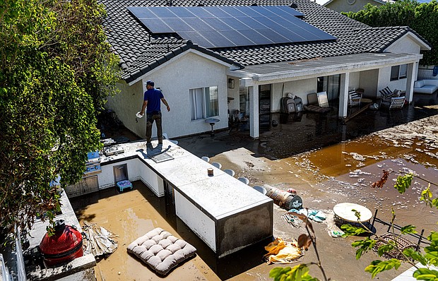 Nick Rodriguez stands on top of an outdoor barbecue seating area at his brother's flooded backyard from the remnants of tropical storm Hilary on August 21 in Cathedral City, California.
Mandatory Credit:	Gina Ferazzi/Los Angeles Times/Getty Images