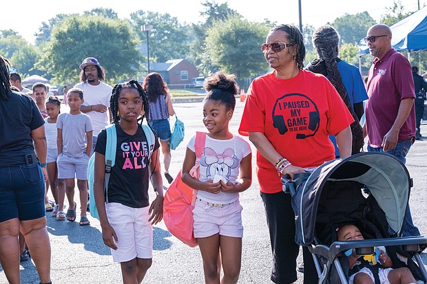 Sisters Treasure Woodson, 10, and Trinity Neville, 7, take in Second Baptist Church’s annual back-to-school event with their grandmother, Diana Neville, and 7-month-old cousin, Daelynn Neville on Saturday.