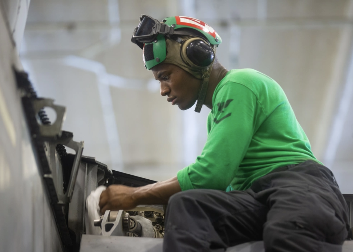 Houston native performs maintenance on a fighter jet in the hangar bay
