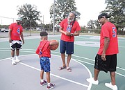 Milton Bell takes time on the court with one of his mentees and godson, Jeremiah Neblett, 7, of Richmond. Also on the court is Bo Jones, 44, left, a coach with Mr. Bell and a former VCU basketball player from 1998-2001. Looking on also is Coach Raymond Neblett, 59, of Ray Neblett’s Inner City Basketball Camps, father of Jeremiah.