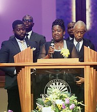 Caroline A. Ouko, the mother of 28-year-old Irvo Noel Otieno stands at the pulpit speaking during her son’s funeral at First Baptist Church of South Richmond in North Chesterfield County Wednesday, March 29, 2023. Standing with her is her eldest son, left, Leon Ochieng, Rev. Al Sharpton and Atty. Benjamin Crump.