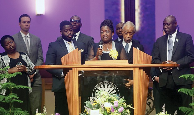 Caroline A. Ouko, the mother of 28-year-old Irvo Noel Otieno stands at the pulpit speaking during her son’s funeral at First Baptist Church of South Richmond in North Chesterfield County Wednesday, March 29, 2023. Standing with her is her eldest son, left, Leon Ochieng, Rev. Al Sharpton and Atty. Benjamin Crump.