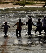 Migrants join hands as they cross the Rio Grande from Mexico into the U.S., on Sept. 21, in Eagle Pass, Texas.
Mandatory Credit:	Eric Gay/AP