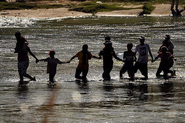 Migrants join hands as they cross the Rio Grande from Mexico into the U.S., on Sept. 21, in Eagle Pass, Texas.
Mandatory Credit:	Eric Gay/AP