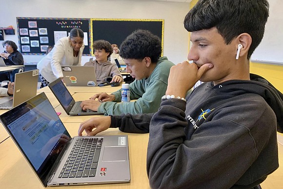 Inside a high school classroom, Bryan Martinez jots down several purchases that would require a short-term savings plan: shoes, phone, ...