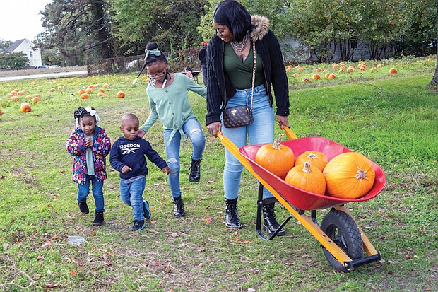 Paris Jennings, 3, Jaki Planton, 1, and Princess Jennings, 7, tag along as Ebony Jennings gets a
few pumpkins for art projects at the Gallmeyer Farms Pumpkin Patch in Henrico County on Oct. 12.