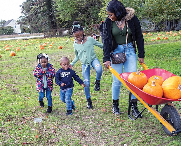 Paris Jennings, 3, Jaki Planton, 1, and Princess Jennings, 7, tag along as Ebony Jennings gets a
few pumpkins for art projects at the Gallmeyer Farms Pumpkin Patch in Henrico County on Oct. 12.
