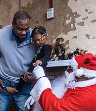 Zeniyah Trent, 3, needs the support of her father, Colby Trent, as she confers with Soul Santa about her Christmas wish list Dec. 2 at the Black History Museum and Cultural Center of Virginia.