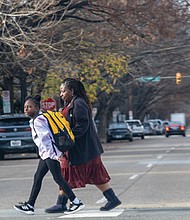 Pedestrians hurry through a crosswalk at 1st and Leigh streets in Jackson Ward. Marked crosswalks indicate locations for pedestrians to cross and signify to motorists to yield to them.