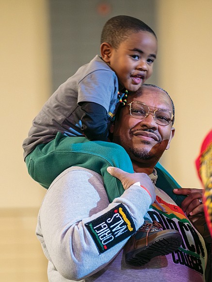Charles Haden, 4, joins his father, Kuchumbi Hayden, as his mother Chenequa Hayden (not shown) participates in the Candle Lighting Ceremony during the 33rd Annual Capital City Kwanzaa Festival at Greater Richmond Convention Center on Dec. 30.