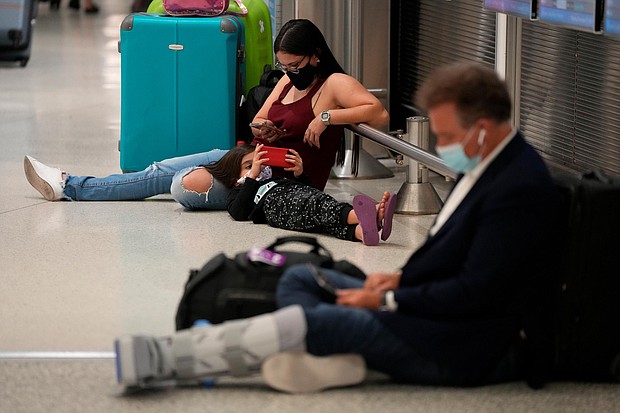 A woman and child wait for their flight alongside another traveler at Miami International Airport in December 2021.
Mandatory Credit:	Rebecca Blackwell/AP