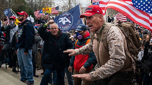 Ray Epps, in the red Trump hat, center, gestures to a line of law enforcement officers, as people gather on the West Front of the U.S. Capitol on January 6, 2021 in Washington, DC.
Mandatory Credit:	Kent Nishimura/Los Angeles Times/Getty Images