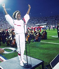 Whitney Houston sings the National Anthem during the pregame show at Super Bowl XXV while tens of thousands of football fans wave tiny American flags in a show of patriotism during the Persian Gulf War in 1991.