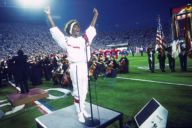 Whitney Houston sings the National Anthem during the pregame show at Super Bowl XXV while tens of thousands of football fans wave tiny American flags in a show of patriotism during the Persian Gulf War in 1991.
