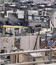 Two people examine a burned house on August 13, 2023, after a fire destroyed much of the historic Maui resort town of Lahaina in Hawaii.
Mandatory Credit:	Sandy Hooper/USA TODAY/Reuters