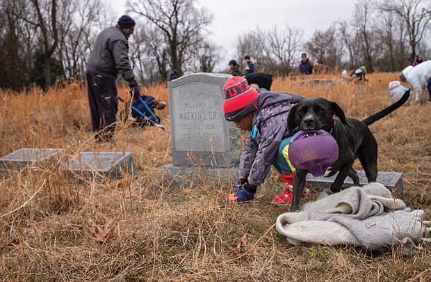While William Dunn, 4, helps clean up Evergreen Cemetery, Teacake is only interested in playing during Friends of East End Cemetery’s Martin Luther King Jr. Day of Service on Jan. 17.