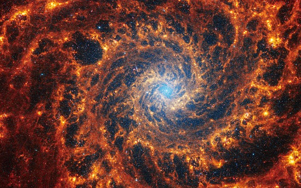 This Webb image shows a densely populated spiral galaxy anchored by a central region that has a light blue haze, known NGC 628. It's 32 million light-years away in the constellation Pisces.
Mandatory Credit:	NASA, ESA, CSA, STScI, J. Lee (STScI), T. Williams (Oxford), PHANGS Team
